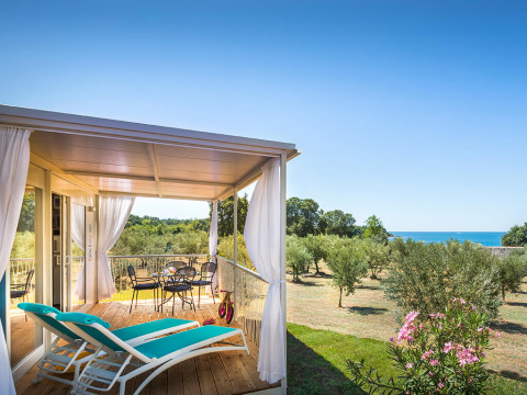 Terrazza coperta con lettini e vista mare presso Miramí Family Village – Prestige Holiday Home.