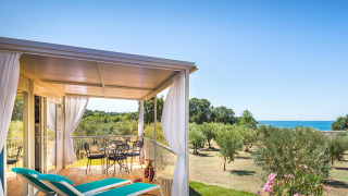 Terrazza coperta con lettini e vista mare presso Miramí Family Village – Prestige Holiday Home.