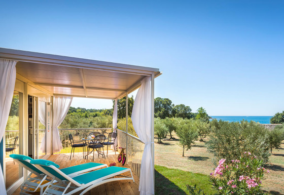 Terrazza coperta con lettini e vista mare presso Miramí Family Village – Prestige Holiday Home.