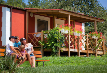 Una famiglia seduta su una panchina davanti a Maravea Premium Holiday Home con fiori e terrazza in legno.