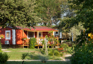 Rood vakantiehuisje met houten veranda te midden van groen bij Aminess Planet Camping Maravea in Kroatië.