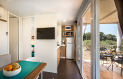 Interno di casetta moderna con cucina, tavolo da pranzo e terrazza al Miramí Family Village, Croazia.