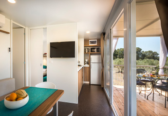 Interno di casetta moderna con cucina, tavolo da pranzo e terrazza al Miramí Family Village, Croazia.