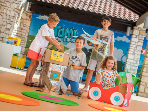 Kinderen spelen met kartonnen robots en auto’s in het kleurrijke speelgebied bij Miramí Family Village, Kroatië.