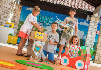 Bambini giocano con robot e auto di cartone colorati nell'area interna del Miramí Family Village, Croazia.