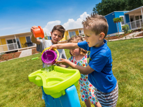 Kinderen spelen buiten met water en emmers bij Miramí Family Village, Aminess Planet Camping Maravea Resort in Kroatië.
