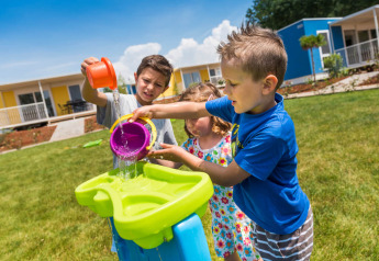 Bambini giocano con secchi d’acqua all’aperto al Miramí Family Village, Aminess Planet Camping Maravea Resort in Croazia.