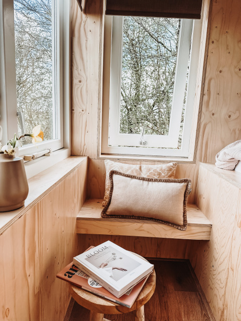 Knusse vensterbank met houten zitje, kussens en boeken in Smûk Fjildhuske lodge, Smûk Recreatie, Nederland.