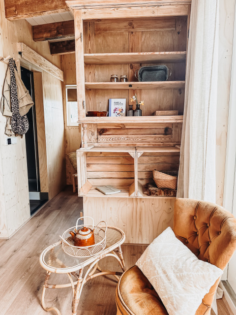 Rincón acogedor con silla y mesa de té en la cabaña Smûk Fjildhuske de Smûk Recreatie, Países Bajos.