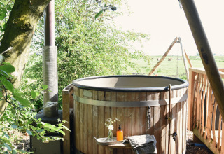 Buiten hot tub bij Smûk Fjildhuske, Smûk Recreatie in Nederland, omgeven door groen en weilanden.