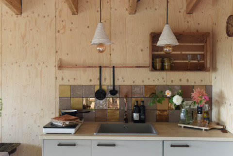 Acogedora cocina pequeña de madera con azulejos de colores y flores en Smûk Tiny, Países Bajos.