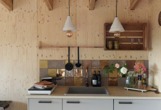 Acogedora cocina pequeña de madera con azulejos de colores y flores en Smûk Tiny, Países Bajos.