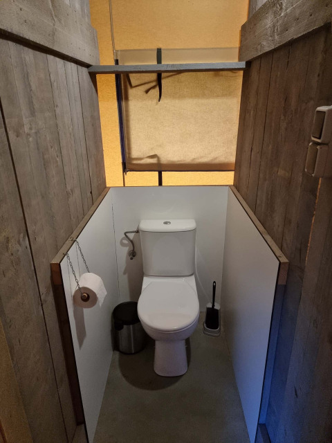 Toilettes dans une tente safari au Recreatiepark De Achterste Hoef aux Pays-Bas, entourées de bois.