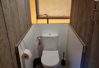 Toilet in een safaritent bij Recreatiepark De Achterste Hoef in Nederland, tussen houten wanden.