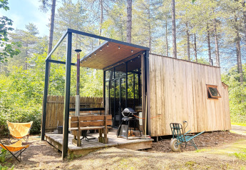 Acogedora cabaña pequeña de madera con terraza, parrilla y banco en el bosque de Cosy Cabins, Limburgo, Bélgica.
