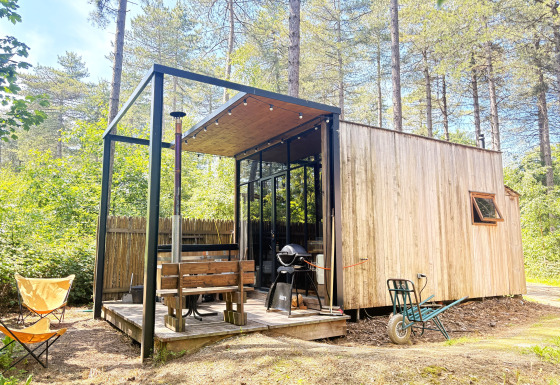 Acogedora cabaña pequeña de madera con terraza, parrilla y banco en el bosque de Cosy Cabins, Limburgo, Bélgica.