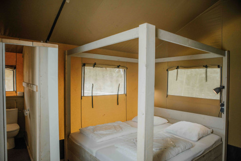 Innenansicht eines Safarizeltes mit Doppelbett und Bad im Veluwepark de Bosgraaf, Niederlande.