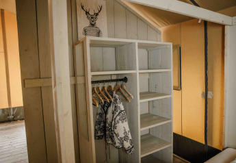 Træ garderobe med tøj og bøjler i en safari telt ved Veluwepark de Bosgraaf, Holland.