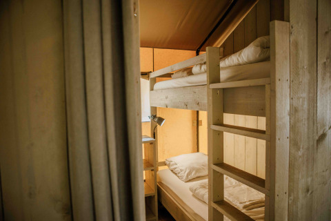 Indvendig udsigt over en safari-telt med køjesenge og blødt lys på Veluwepark de Bosgraaf i Holland.