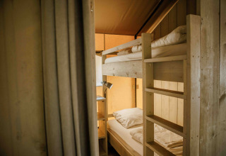 Vista interior de una tienda safari con literas y luz cálida en Veluwepark de Bosgraaf, Países Bajos.