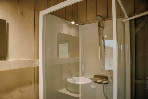 Badezimmer im Safarizelt im Veluwepark de Bosgraaf, Niederlande, mit moderner Dusche und Waschbecken.
