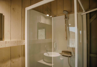 Baño en tienda safari en Veluwepark de Bosgraaf, Países Bajos, con ducha moderna y lavabo elegante.