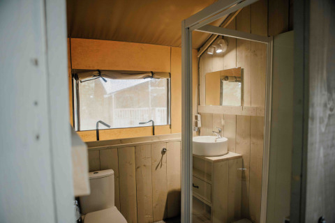 Safari-Zeltbadezimmer mit Holzverkleidung, Waschbecken und Fenster im Veluwepark de Bosgraaf, Niederlande.
