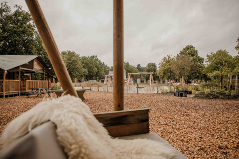 Blick auf Spielplatz und Safari-Zelt im Veluwepark de Bosgraaf, Niederlande, von einer Sitzbank aus.