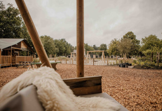 Udsigt over legeplads og safari-telt ved Veluwepark de Bosgraaf, Holland, set fra en hyggelig siddeplads.
