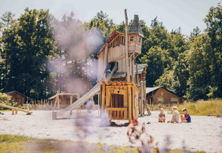 Børn leger ved en trælegeplads foran safaritelte i Veluwepark de Bosgraaf, Holland, om sommeren.