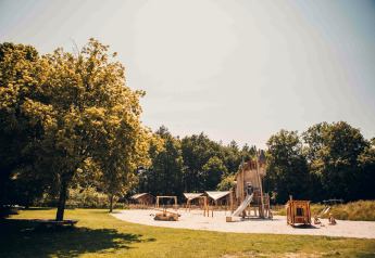 Parco giochi con strutture in legno e scivolo vicino a tenda safari a Veluwepark de Bosgraaf nei Paesi Bassi.