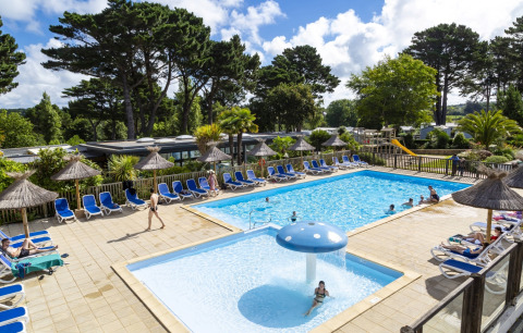 Udendørs swimmingpoolområde med liggestole og parasoller på Flower Camping Port de la Chaîne i Bretagne.