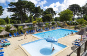 Outdoor swimming pool area with deck chairs and umbrellas at Flower Camping Port de la Chaîne, Brittany.