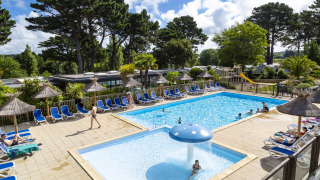Espace piscine extérieure avec transats et parasols au Flower Camping Port de la Chaîne en Bretagne.