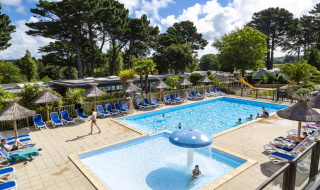 Espace piscine extérieure avec transats et parasols au Flower Camping Port de la Chaîne en Bretagne.