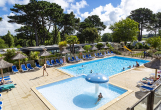 Buitenzwembad met ligstoelen en parasols op Flower Camping Port de la Chaîne in Bretagne.