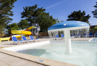 Outdoor pool with water slide and mushroom fountain at Flower Camping Port de la Chaîne in Brittany, France.