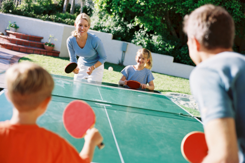 Gezin speelt buiten tafeltennis bij Flower Camping Port de la Chaîne, een vakantiepark in Bretagne, Frankrijk.
