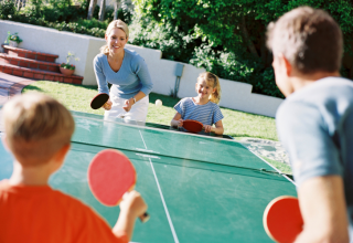 Familie spielt Tischtennis im Freien im Flower Camping Port de la Chaîne, Ferienpark in der Bretagne, Frankreich.