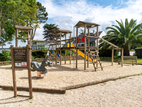 Aire de jeux avec structure en bois et toboggan au Flower Camping Port de la Chaîne en Bretagne, France.