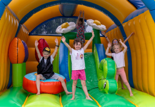 Niños juegan felices en un castillo inflable colorido con flores en Flower Camping Port de la Chaîne, Bretaña, Francia.