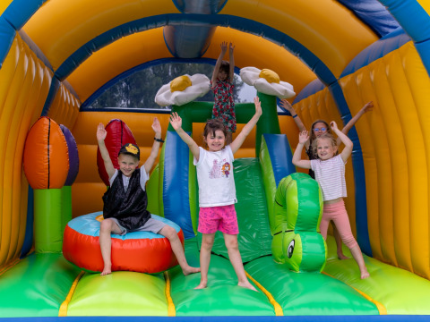 Kinderen spelen vrolijk in een kleurrijk springkasteel met bloemen bij Flower Camping Port de la Chaîne, Bretagne.