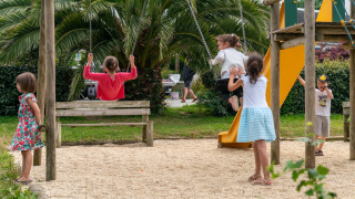 Des enfants jouent sur une aire de jeux avec balançoires et toboggan au Flower Camping Port de la Chaîne, Bretagne.