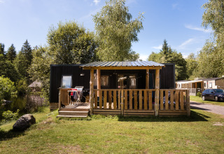 Casetta in legno con veranda al Flower Camping La Sténiole, Grand Est, Francia, immersa nella natura.