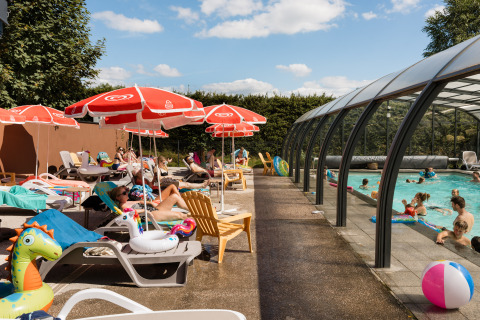 Außenpoolbereich im Flower Camping La Sténiole mit Menschen, Sonnenliegen und Sonnenschirmen im Sommer.