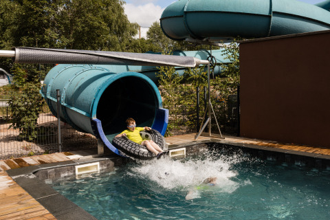 Bambini che giocano sullo scivolo d'acqua a Flower Camping La Sténiole, parco vacanze in Grand Est, Francia.