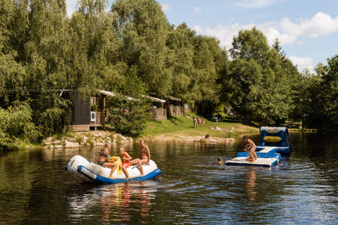 Kinder spielen auf aufblasbaren Wasserspielzeugen im See bei Flower Camping La Sténiole, Grand Est, Frankreich