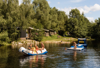 Kinder spielen auf aufblasbaren Wasserspielzeugen im See bei Flower Camping La Sténiole, Grand Est, Frankreich