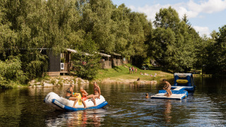 Børn leger på oppustelige vandlegesager i en sø ved Flower Camping La Sténiole i Grand Est, Frankrig