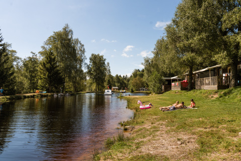 Parc de vacances Flower Camping La Sténiole en Grand Est, France, avec des gens au bord du lac.